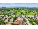 Aerial view showcases a brick condo building close to a golf course and road with beautiful green landscaping at 2400 E Cherry Creek South Dr # 207, Denver, CO 80209
