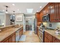 Galley style kitchen with stainless appliances, wood cabinets, granite countertops and a skylight at 1582 W Briarwood Ave, Littleton, CO 80120