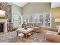 Sunlit living room features a stone fireplace and a wall of windows overlooking the backyard at 1582 W Briarwood Ave, Littleton, CO 80120