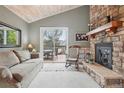 Cozy living room with a stone fireplace, sliding glass door, and vaulted ceiling with a wooden finish at 1582 W Briarwood Ave, Littleton, CO 80120