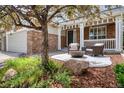 Inviting covered porch with comfortable seating, mature landscaping, and stone accents at 22898 Addington Pl, Parker, CO 80138