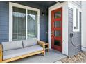 Inviting front porch featuring a modern red door, comfortable seating, and stylish accents at 1954 S Poplar Ct, Denver, CO 80224