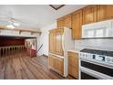 Kitchen with wood cabinets, white appliances, and hardwood floors at 11143 W Ohio Pl, Lakewood, CO 80226