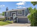 Two-story gray home featuring an attached garage, lush front lawn and manicured flower beds at 3965 S Fundy Cir, Aurora, CO 80013