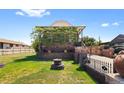 View of the brick home with a landscaped yard, gated driveway, and mature greenery at 5960 Glencoe St, Commerce City, CO 80022
