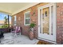 Cozy brick front porch with seating, a decorative door, and brick accents at 5960 Glencoe St, Commerce City, CO 80022