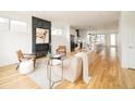Open-concept living area with fireplace, wood floors, and modern kitchen in the background at 3929 Newton St, Denver, CO 80211