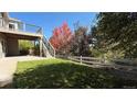 Landscaped backyard with deck, stairs, and wooden fence at 958 Bramblewood Dr, Castle Pines, CO 80108