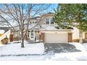 Two-story house with brick and siding exterior, attached garage, and snow-covered landscaping at 958 Bramblewood Dr, Castle Pines, CO 80108