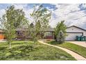 Charming brick home featuring a well-manicured lawn, inviting walkway, detached garage, and mature trees at 2986 W Union Ave, Englewood, CO 80110