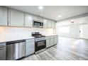 Open kitchen featuring stainless steel appliances, light gray cabinets, and laminate flooring at 901 S Osceola St, Denver, CO 80219