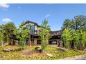 Beautiful two-story home with a large deck, stone accents, and mature trees enhancing the landscape at 26116 Chief Hosa Rd, Golden, CO 80401