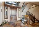 Elegant foyer with slate flooring, a wooden staircase, and a stylish bench creating a welcoming entrance at 26116 Chief Hosa Rd, Golden, CO 80401