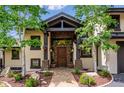 Inviting front entrance featuring a stone walkway, wooden door, and decorative flower baskets at 26116 Chief Hosa Rd, Golden, CO 80401