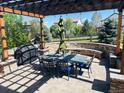 Inviting outdoor patio with pergola, stone seating area, grill, and dining set at 6738 Esmeralda Dr, Castle Rock, CO 80108