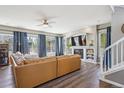 Inviting living room featuring hardwood floors, large windows with curtains, and a cozy fireplace with a mounted TV at 282 N De Gaulle St, Aurora, CO 80018