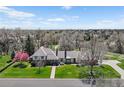 A beautiful view of the home showing the driveway, mature trees, and front yard at 21 Huntwick Ln, Cherry Hills Village, CO 80113