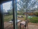 View of a shaded backyard with a patio, wooden fence, mature trees, and lush green grass at 3811 Lisbon Ct, Denver, CO 80249