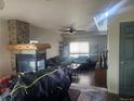 Cozy living room featuring a stone fireplace, beamed mantel, wood floors, and a ceiling fan at 3811 Lisbon Ct, Denver, CO 80249