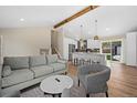 Open concept living room with wood beam, kitchen view, and neutral toned contemporary furniture at 18866 W 59Th Pl, Golden, CO 80403