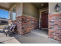 Inviting front porch with brick accents and seating area, creating a warm and welcoming entrance at 26909 E Cedar Ave, Aurora, CO 80018