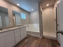 Well-lit bathroom featuring double sink vanity, soaking tub and separate shower, modern fixtures, and wood flooring at 48250 Shetland Dr, Bennett, CO 80102