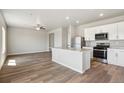 Modern kitchen featuring stainless steel appliances, a center island, and hardwood floors with an open concept to living area at 48250 Shetland Dr, Bennett, CO 80102