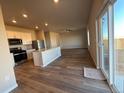 Open concept living space boasts modern kitchen with stainless appliances and sleek wood flooring throughout at 48250 Shetland Dr, Bennett, CO 80102