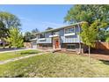 Charming two-story home boasting an inviting facade with green lawn and an orange front door at 4381 Dixon Dr, Westminster, CO 80031