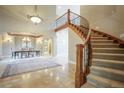 Grand foyer with a curved staircase, chandelier, and travertine tile leading to the dining area at 18720 Lake Dr, Monument, CO 80132