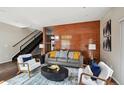 Living room with gray sofa, two chairs, decorative rug and wood accent wall at 3195 Blake St # 106, Denver, CO 80205