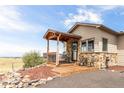 Covered porch with stone feature wall and wooden deck at 8408 Vinegarroon Rd, Parker, CO 80138