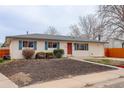 Single-story home featuring a well-maintained front yard, trimmed bushes, and a vibrant red front door at 1056 S Macon Way, Aurora, CO 80012