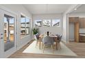 Modern dining room featuring a stylish table setting, ample natural light, and hardwood floors at 21202 E 63Rd Dr, Aurora, CO 80019