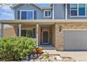Inviting home featuring a brick facade, covered porch, manicured bushes, and two-car garage at 14185 W Warren Cir, Lakewood, CO 80228