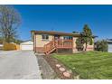 Lovely single-story brick home featuring a wooden front porch, green lawn, and a detached garage with an extended driveway at 3871 Moore St, Wheat Ridge, CO 80033