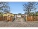 Gated driveway leads to a yellow house, garage, and basketball hoop at 15325 W 32Nd Ave, Golden, CO 80401