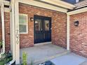 Inviting front entrance featuring a brick facade, black double doors, and modern light fixtures at 7079 S Locust Pl, Centennial, CO 80112