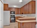 Functional kitchen showcasing wooden cabinetry, a microwave, and an adjacent breakfast bar at 6930 E Girard Ave # 106, Denver, CO 80224