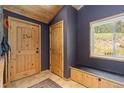 Home entryway featuring a wooden door, tiled floors, and a bench with storage at 24030 San Isabel Rd, Indian Hills, CO 80454