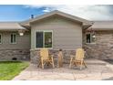 Inviting front patio with stone pavers and wooden chairs, creating a cozy outdoor seating area at 24030 San Isabel Rd, Indian Hills, CO 80454