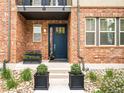 Charming brick home featuring a striking blue front door, rock garden, and elegant potted plants at 181 S Monaco Pkwy, Denver, CO 80224