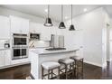Modern kitchen with white cabinets, stainless steel appliances, granite counters, and island seating at 181 S Monaco Pkwy, Denver, CO 80224