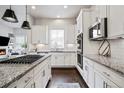 Modern kitchen boasts stainless appliances, granite countertops, stylish backsplash, and dark hardwood flooring at 181 S Monaco Pkwy, Denver, CO 80224