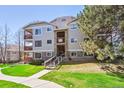 Multi-story building with stone accents, multiple balconies, manicured lawn, and mature trees at 7680 Depew St # 1404, Arvada, CO 80003