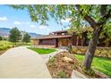 Charming home featuring wood siding, stone accents, and a tile roof surrounded by mature landscaping at 10895 Pheasant Run, Littleton, CO 80125