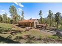 A cozy home nestled in a wooded area with a covered porch and deck for enjoying nature at 34 Normandy Rd, Evergreen, CO 80439