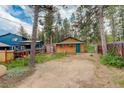Wood sided cabin with a green door and trim and a large backyard full of native trees at 184 Signal Rock Rd, Golden, CO 80403