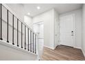 Inviting entryway featuring wood floors, a staircase with black railings, and white trim at 1415 Orchard St, Brighton, CO 80601