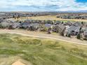 An aerial shot of a residential community surrounded by green spaces and golf course fairways at 15004 Verbena St, Thornton, CO 80602